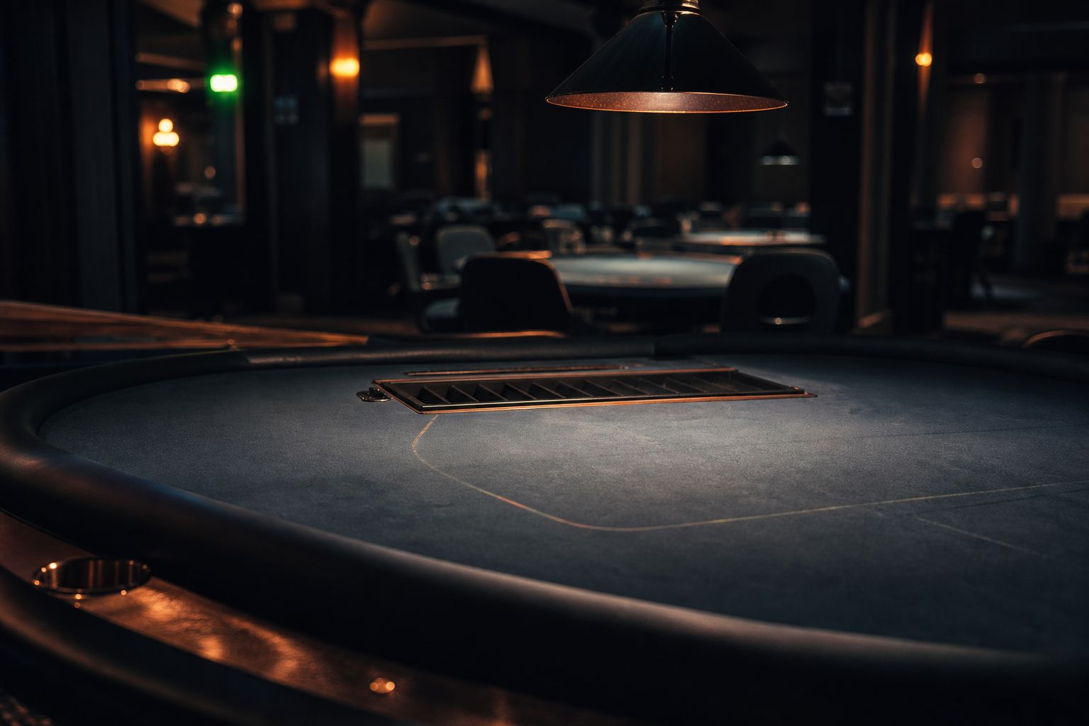 Mesa de casino vacía con las fichas ya recogidas bajo una lámpara que se apaga